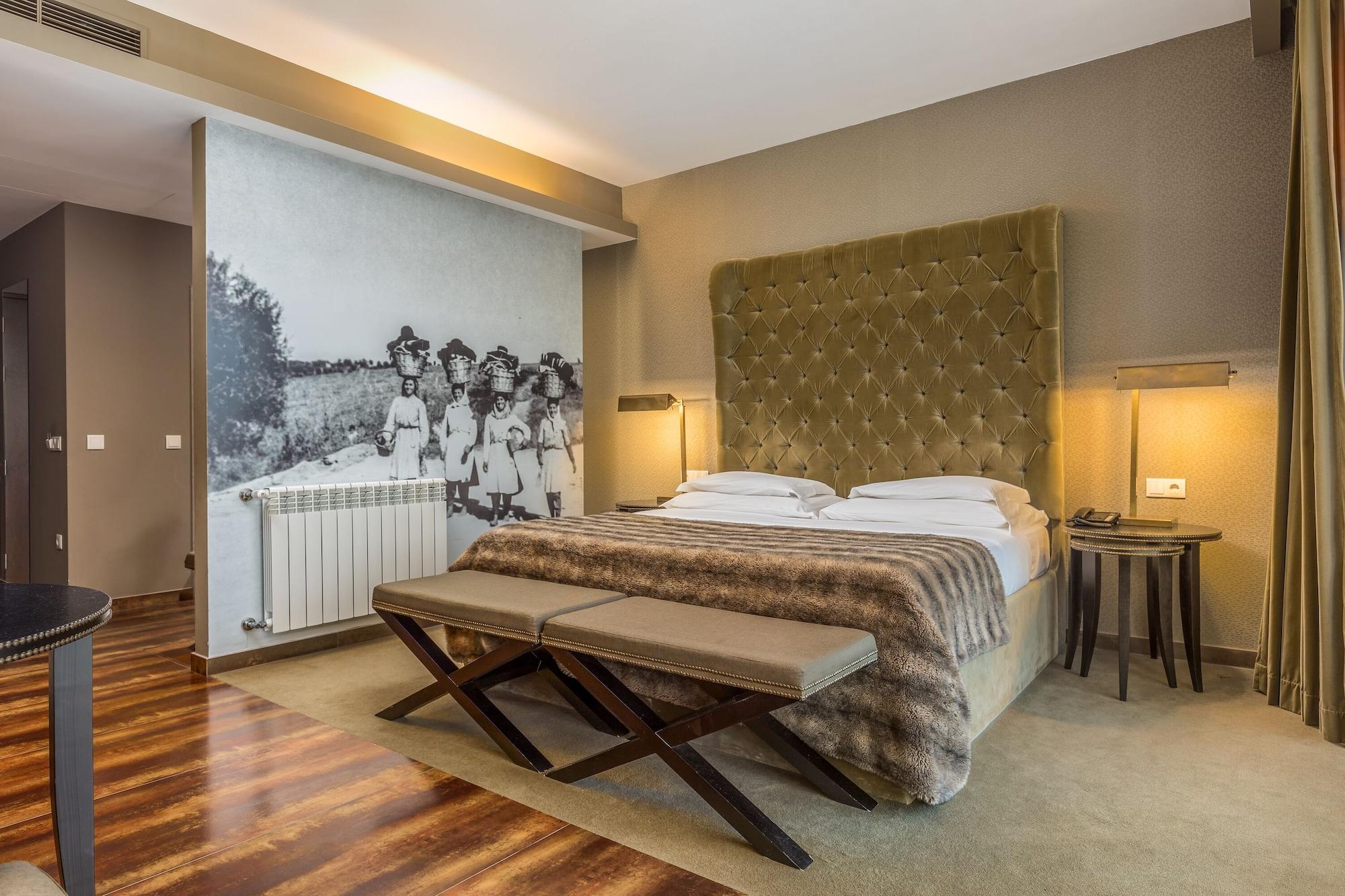 Ap Lago Montargil - Conference & Spa Buitenkant foto The photo shows a modern hotel room with a large, plush bed that has a tufted, green headboard. The bedding is white with a textured blanket at the foot of the bed. A decorative wall behind the bed features a black and white mural of children in a fi